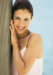Woman leaning against wooden pole, smiling