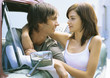 Photo: Young woman standing next to pick-up truck with arm around boyfriend in driver's seat Young woman standing next to pick-up truck with arm around boyfriend in driver's seat