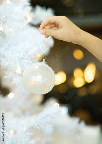 Photo: Child hanging christmas ornament on tree Child hanging christmas ornament on tree