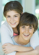 Girl hugging preteen boy from behind, portrait