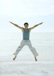 Man jumping spreadeagled on beach