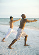 Photo: Two men doing relaxation exercise on beach Two men doing relaxation exercise on beach