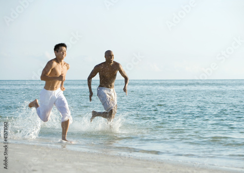Photo: Two men running in surf Two men running in surf
