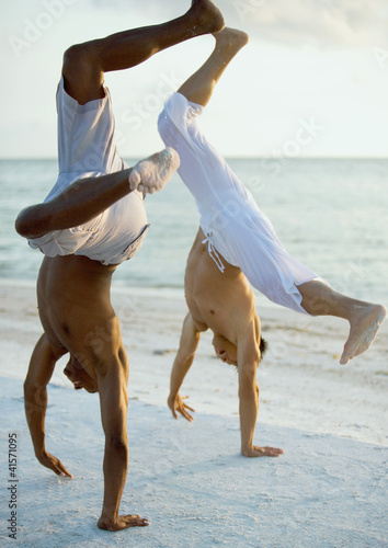 Photo: Two men turning cartwheels on beach Two men turning cartwheels on beach