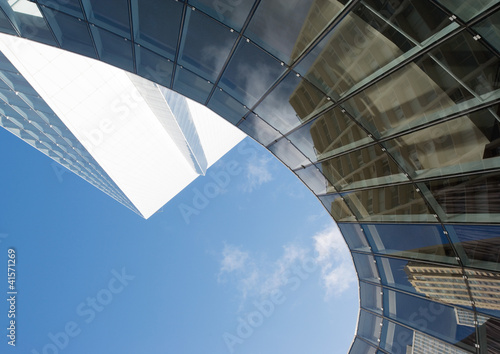 Photo: Skyscraper with reflection of buildings on facade, low angle, abstract view Skyscraper with reflection of buildings on facade, low angle, abstract view