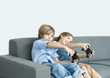 Boy and girl playing video game, holding out joysticks on sofa