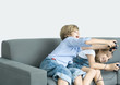 Boy and girl playing video game, holding out joysticks on sofa