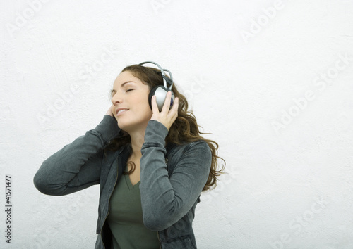 Photo: Young woman listening to headphones, eyes closed, white background Young woman listening to headphones, eyes closed, white background