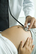 Photo : Doctor listening to pregnant woman's stomach with stethoscope Doctor listening to pregnant woman's stomach with stethoscope