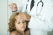 Doctor feeling boy's forehead and holding thermometer