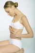 Woman sitting in underclothes, touching abdomen