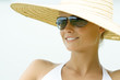 Young woman wearing sunhat and sunglasses, smiling