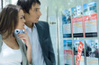 Photo: Couple standing next to window of real estate agency, looking at for rent and for sale signs Couple standing next to window of real estate agency, looking at for rent and for sale signs