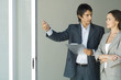 Photo: Male real estate agent showing house to female client, standing by sliding glass door, woman looking out, smiling Male real estate agent showing house to female client, standing by sliding glass door, woman looking out, smiling