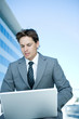 Young businessman outdoors, using laptop computer, looking down