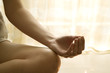 Teenage girl sitting in lotus position, cropped view of hand