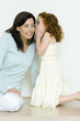 Little girl whispering to mother