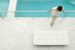 Woman standing on terrace, leaning against railing, swimming pool in background