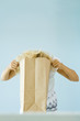 Woman putting head into paper grocery bag
