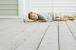 Boy lying on the ground next to starfish, head resting on arm