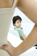 Boy sulking, looking over shoulder at mother in foreground with hand on hip