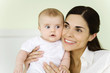 Mother holding infant, smiling, portrait