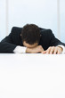 Businessman with head down, arm over eyes