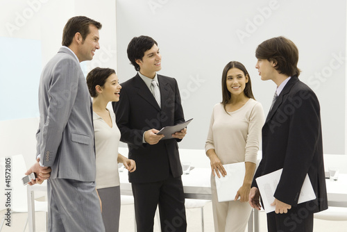 Photo: Group of business associates standing together, smiling, chatting Group of business associates standing together, smiling, chatting