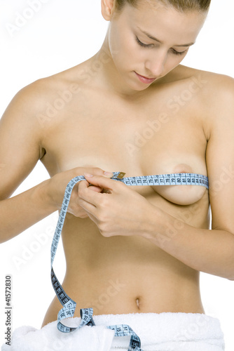Photo: Nude woman measuring breasts with measuring tape, looking down Nude woman measuring breasts with measuring tape, looking down