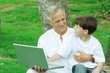 Boy sitting on grandfather's lap, using laptop computer