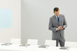 Businessman standing beside conference table, looking down at cell phone