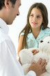 Pediatrician with young patient, girl holding teddy bear