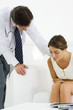 Woman bending over, holding stomach, doctor leaning over to check on her