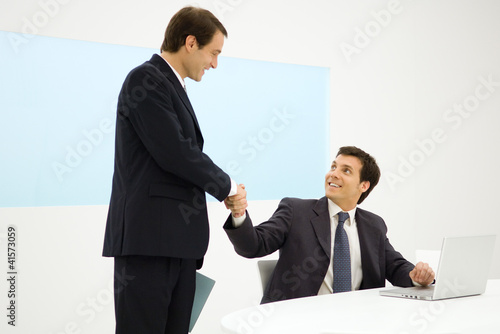 Photo: Businessmen shaking hands, smiling at each other Businessmen shaking hands, smiling at each other