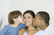 Husband and son kissing woman's cheeks, woman smiling at camera