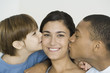 Husband and son kissing woman's cheeks, woman smiling at camera
