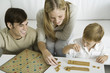 Family playing board game together, mother arranges game pieces