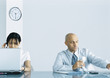 Office, man holding telephone while woman uses computer