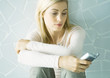 Woman sitting with arms folded on knees, looking at cell phone