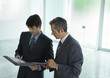Two businessmen looking at file in lobby
