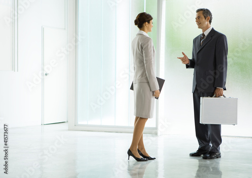 Photo: Businessman and businesswoman talking in lobby Businessman and businesswoman talking in lobby