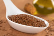 Brown flax seeds on ceramic spoon with linseed oil