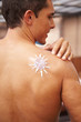 Mann mit Sonnencreme auf Rücken