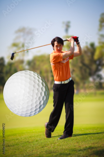 Photo: A golf ball just coming off the tee from a golfer in swing A golf ball just coming off the tee from a golfer in swing