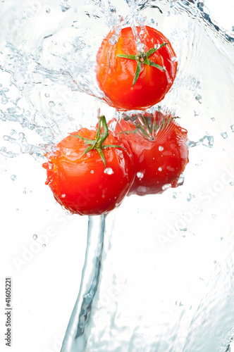 Photo: Three Fresh red Tomatoes in splash of water Isolated on white ba Three Fresh red Tomatoes in splash of water Isolated on white ba