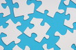 White Jigsaw pieces on blue paper background White Jigsaw pieces on blue paper background