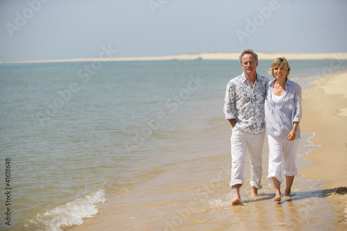 Photo: Middle-aged couple strolling along the shore Middle-aged couple strolling along the shore