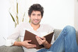 a man reading a book on couch