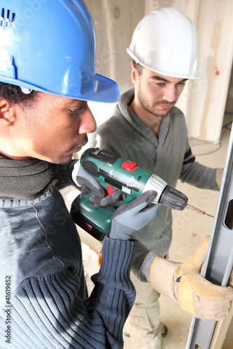 Photo: black and white carpenters at work with electric drill black and white carpenters at work with electric drill