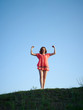 Foto: The young woman in an orange dress, costs on a green hill The young woman in an orange dress, costs on a green hill
